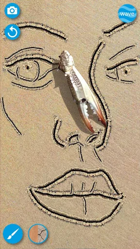 Portrait face drawn in sand with brush tool creating eyes, nose, and mouth features in sand drawing app